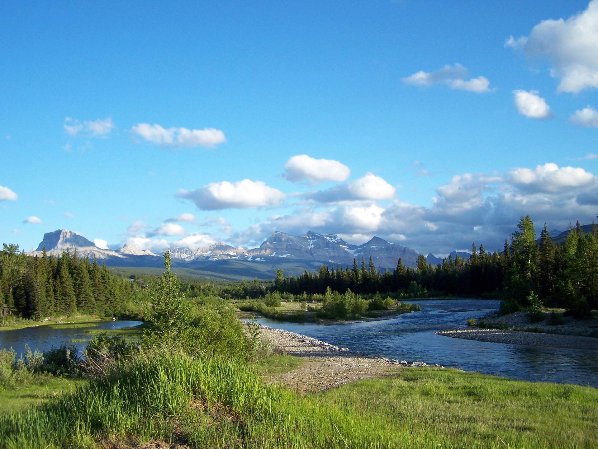 A river winding through a mountain prairie in the sun